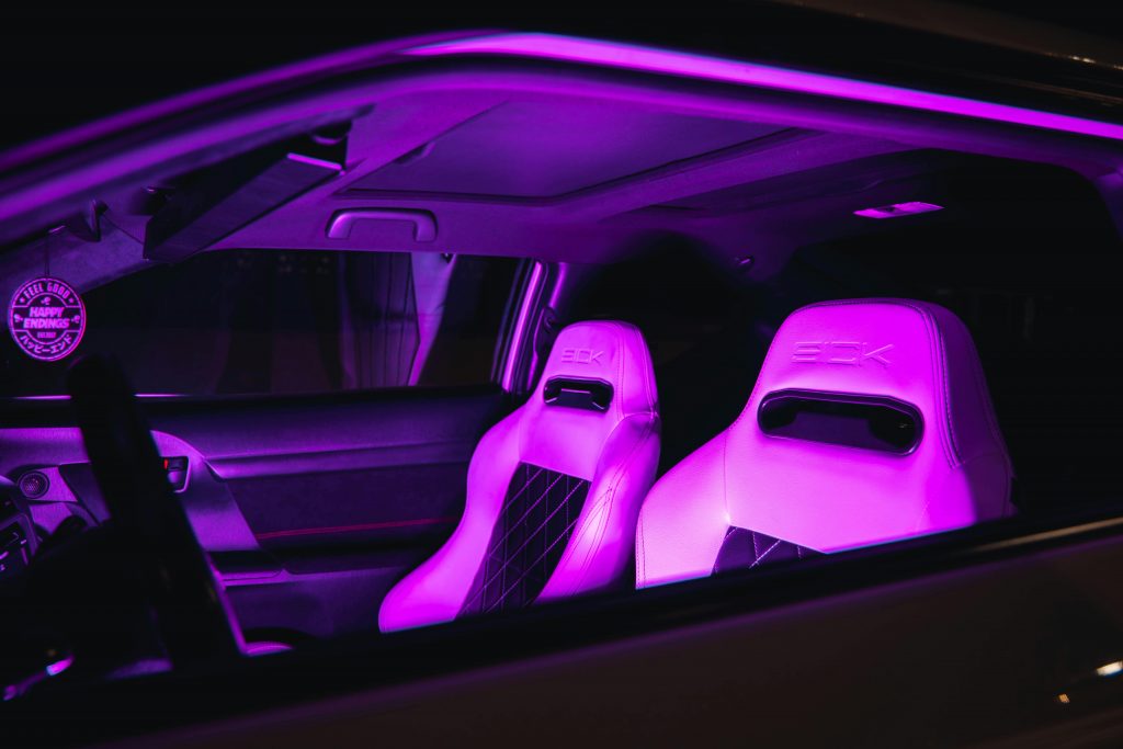 Luxury car interior with neon purple illuminated leather seats, creating a modern and vibrant ambiance.
